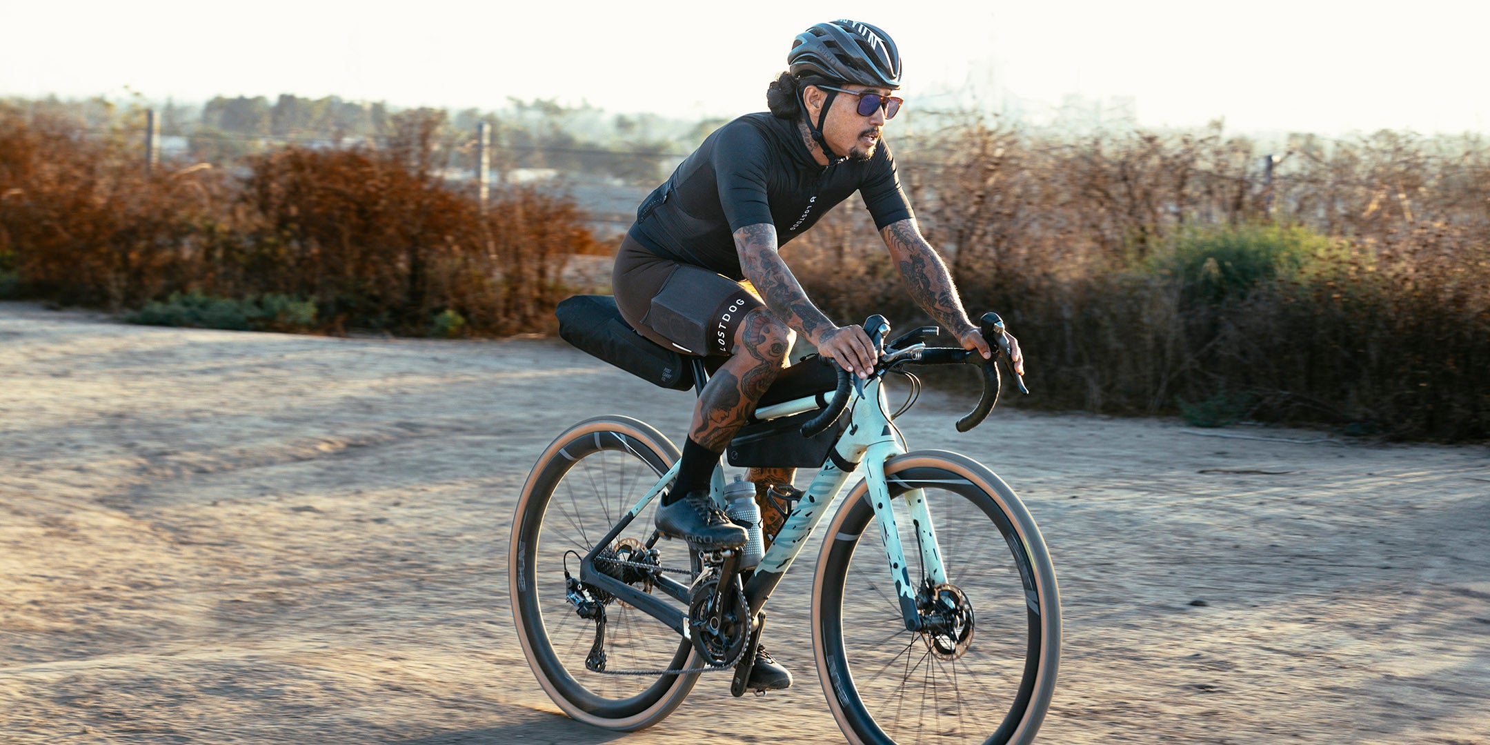 A cyclist with the Post Carry Co. Slim Frame Pack, Top Tube Pack, and Seat Pack mounted his a gravel bike