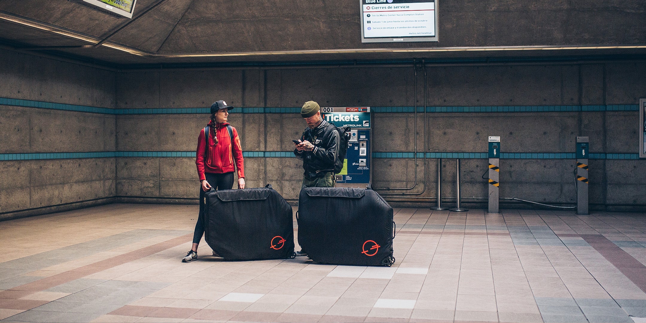 2 people next to the Post Carry Co. Transfer Case at a transit terminal