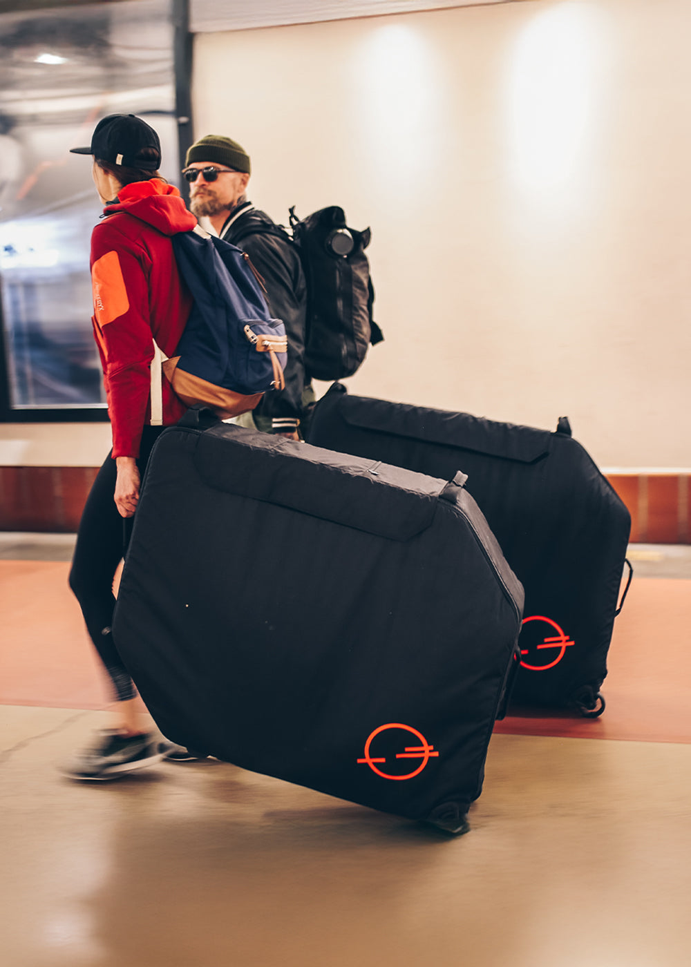 2 people rolling the Post Carry Co. Transfer Case through a transit terminal